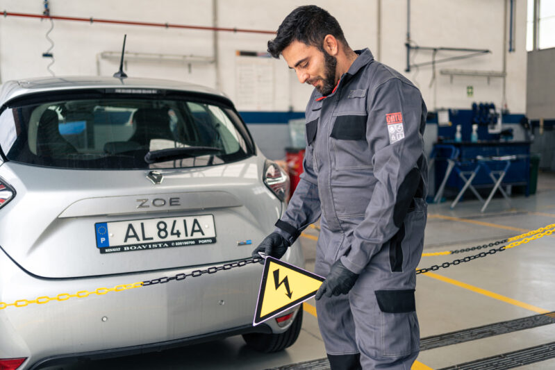 Glass professional placing safety indications on an electric car during maintenance.